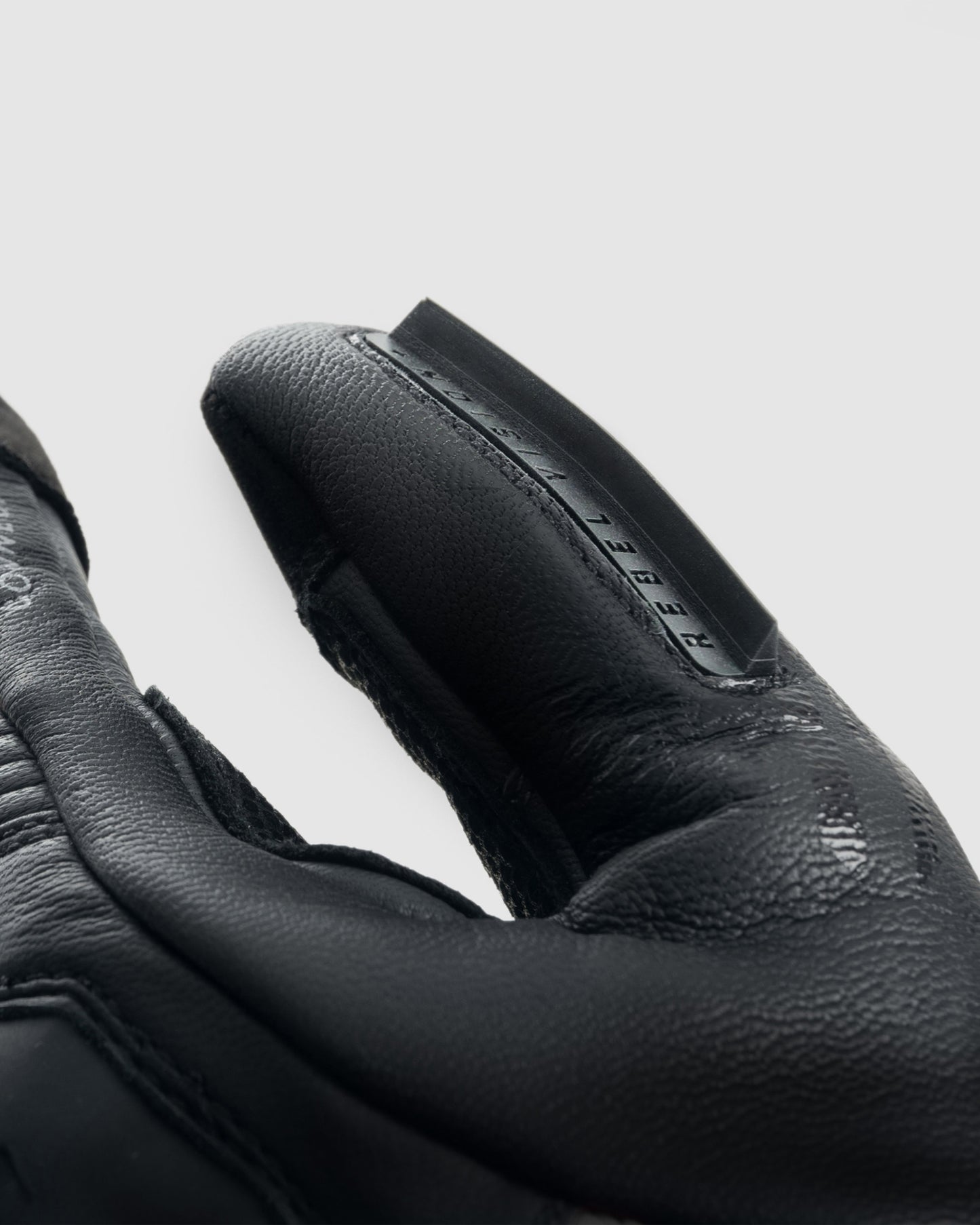 Close-up of black gloves with a brand logo on a light gray background