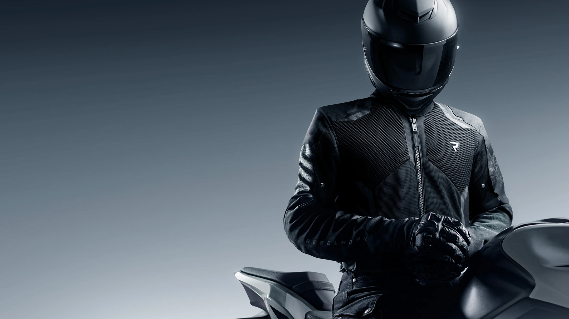 Person wearing a black motorcycle helmet and jacket on a motorcycle with a dark background